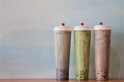 Elegant presentation of three bubble tea flavors in sealed tall cups with red heart lids.