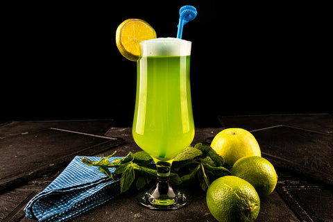 Vibrant green cocktail with fresh lime and apple on a dark background.