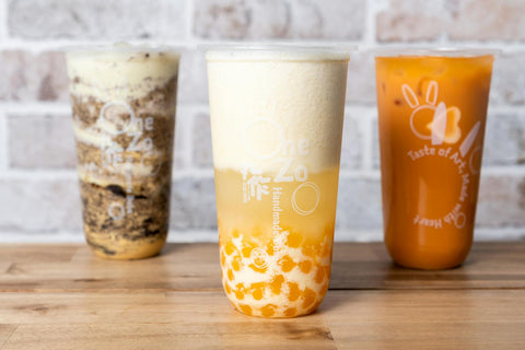 A variety of bubble teas including fruit and milk flavors served on a wooden table.