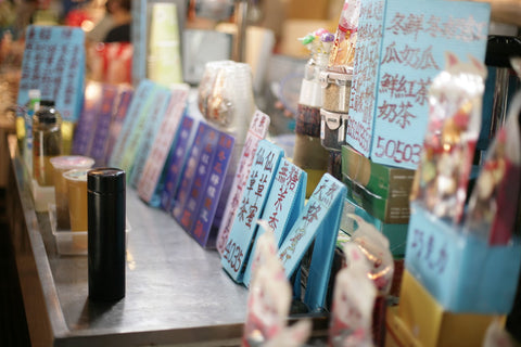 A bustling juice stand with colorful signs at a night market. Vibrant atmosphere.