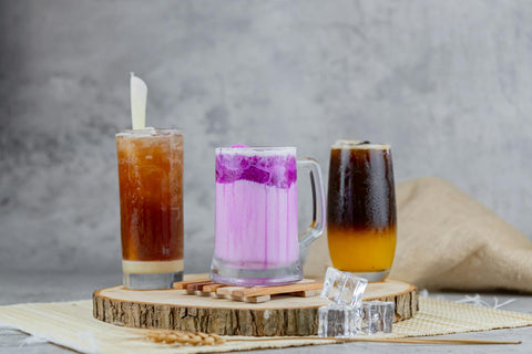 A variety of vibrant iced beverages displayed on a rustic wooden platter, ideal for food and drink presentations.