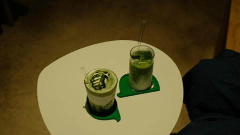 Two creative matcha drinks on a white table with a minimalistic setup.