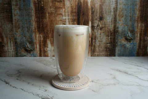 A refreshing iced latte in a clear glass on a stylish marble surface with a rustic wooden background.
