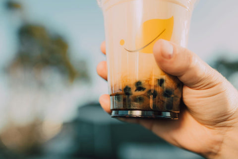Vibrant image of a hand holding a bubble tea cup with a blurred background. Refreshing and trendy.