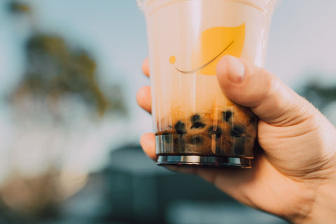 Vibrant image of a hand holding a bubble tea cup with a blurred background. Refreshing and trendy.