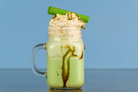 Close-up of a delicious matcha frappe topped with whipped cream and a wafer roll.