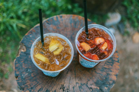 Overhead shot of two fruity iced beverages on a wooden surface outdoors.