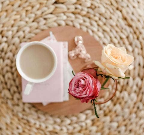 Elegant coffee scene with roses and books on a wicker mat. Perfect for serene morning vibe.